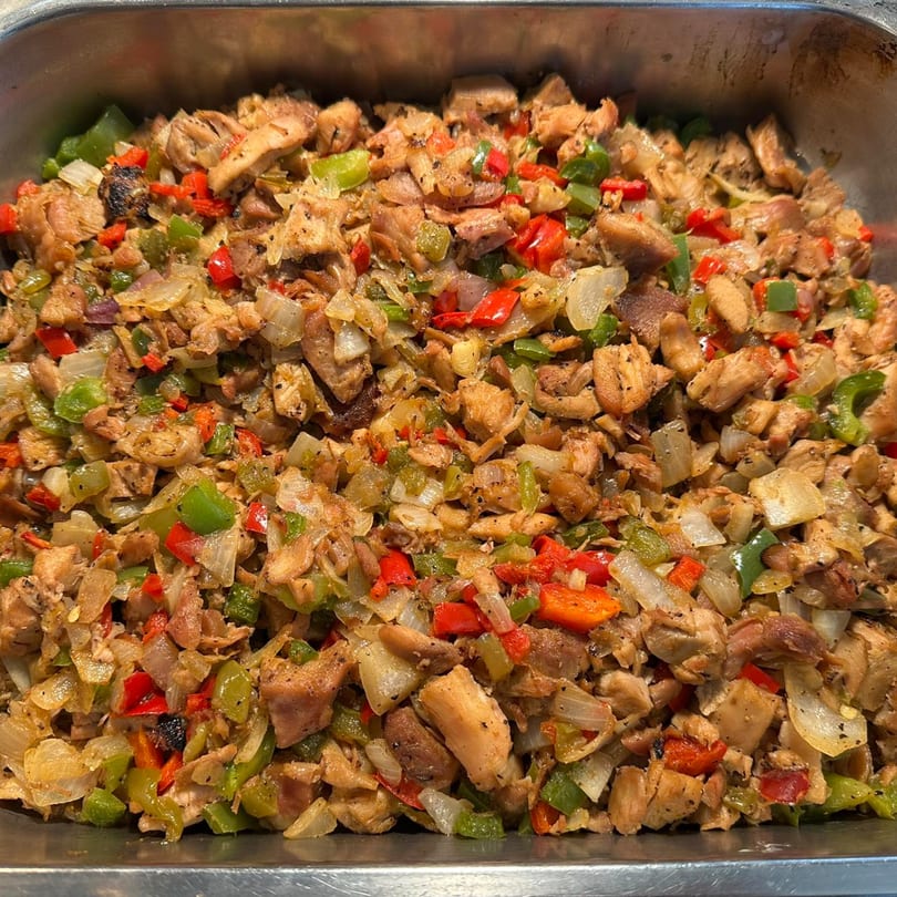 A close-up of Filipino sisig, a savory dish with chopped meat, onions, and red and green bell peppers.